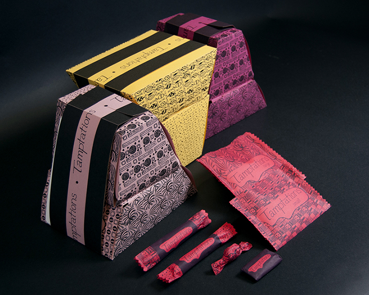 three trapezoid shaped boxes coloured lavender, yellow and red and covered in patterns with bellybands around them. The bellyband reads Tamptations. In front of the boxes are 2 small candy-like pouches, and 4 smaller candy wrappers. All are sitting on a black backdrop.